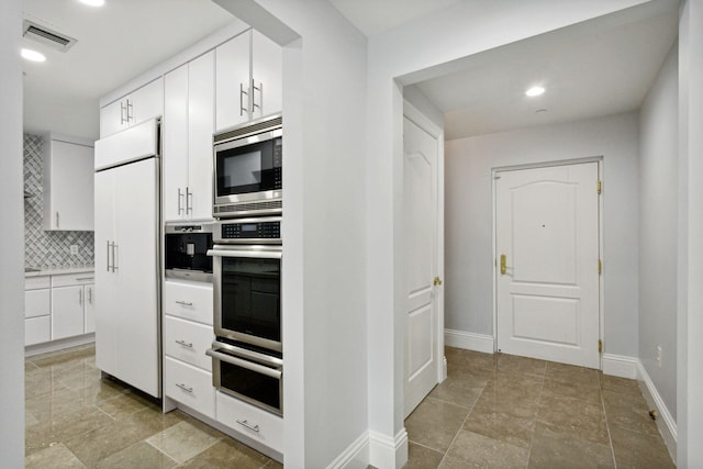 kitchen featuring baseboards, visible vents, built in appliances, a warming drawer, and backsplash