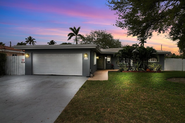 ranch-style house with fence, stucco siding, a lawn, a garage, and driveway