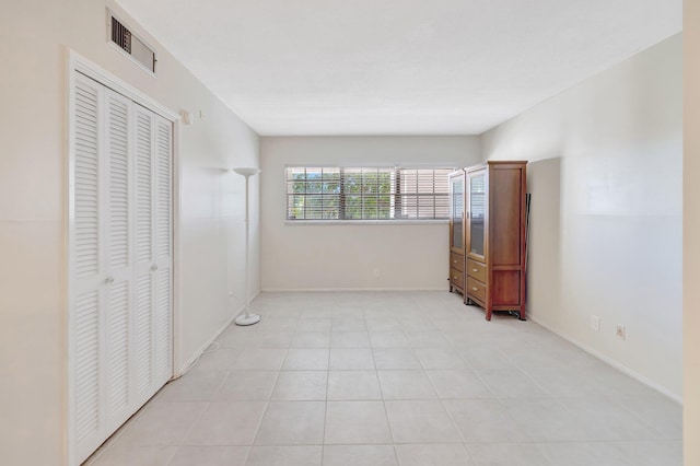 unfurnished bedroom with visible vents, baseboards, a closet, and light tile patterned flooring