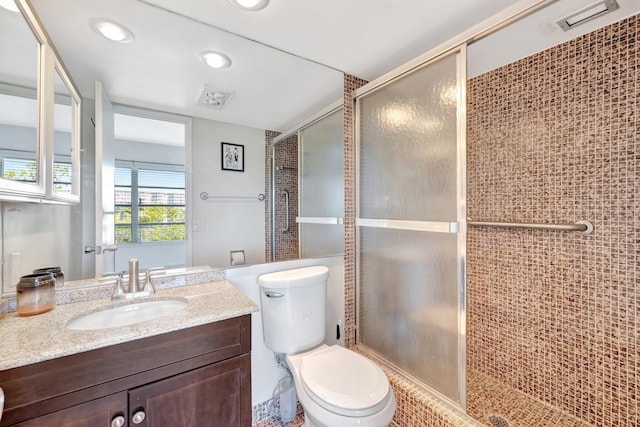 bathroom with visible vents, vanity, a shower stall, and toilet