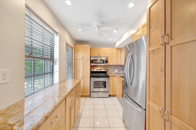 kitchen featuring light brown cabinets, backsplash, stainless steel appliances, light tile patterned floors, and light stone countertops