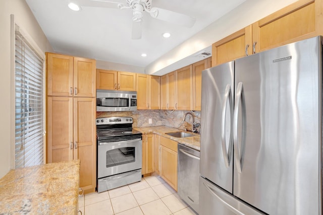 kitchen with light brown cabinets, a sink, tasteful backsplash, appliances with stainless steel finishes, and light tile patterned floors