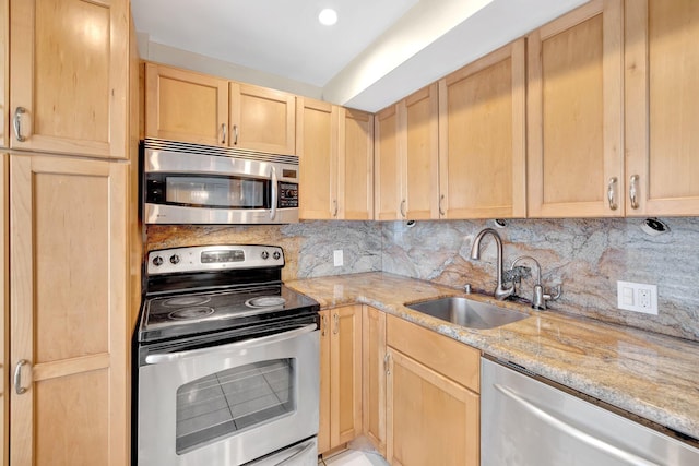 kitchen featuring tasteful backsplash, light stone countertops, light brown cabinetry, stainless steel appliances, and a sink