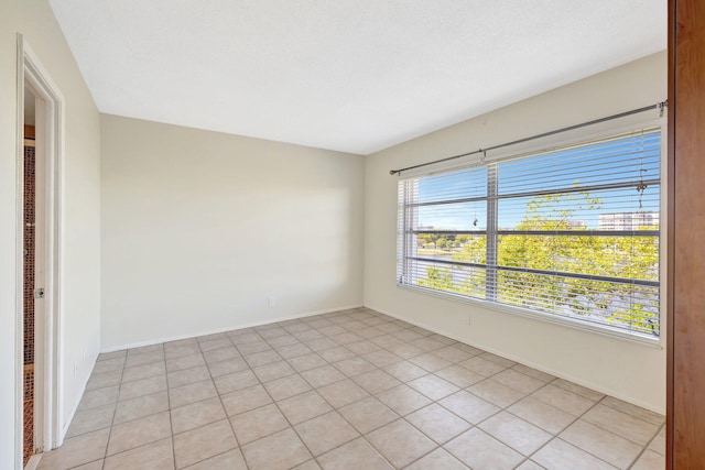 unfurnished room with light tile patterned flooring and baseboards