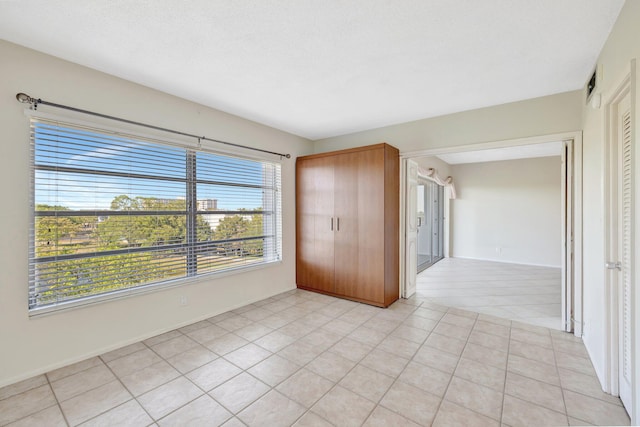 unfurnished room featuring light tile patterned floors and baseboards