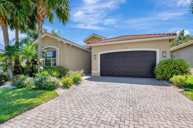 mediterranean / spanish-style house with stucco siding, decorative driveway, and an attached garage