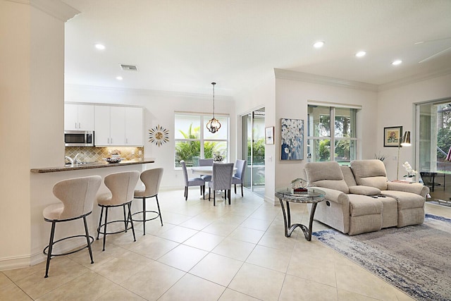 living area with visible vents, ornamental molding, recessed lighting, light tile patterned floors, and baseboards