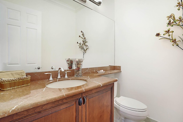 bathroom featuring toilet, ornamental molding, and vanity