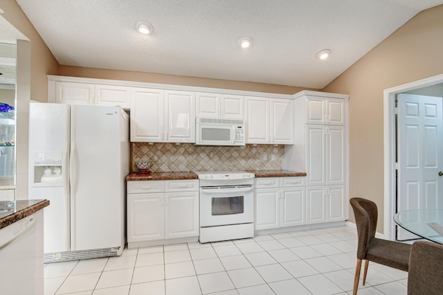 kitchen with light tile patterned floors, white cabinets, white appliances, and lofted ceiling