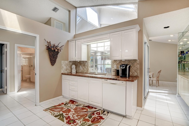 kitchen featuring light tile patterned floors, white cabinetry, lofted ceiling, a sink, and dishwasher