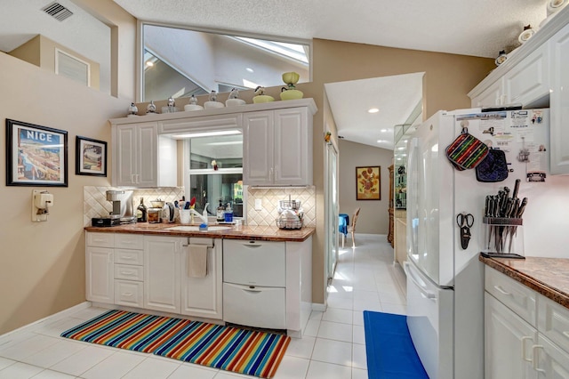 6089 Bay Isles Dr, Boynton Beach, FL 33437 - kitchen with visible vents, a sink, freestanding refrigerator, light tile patterned floors, and lofted ceiling