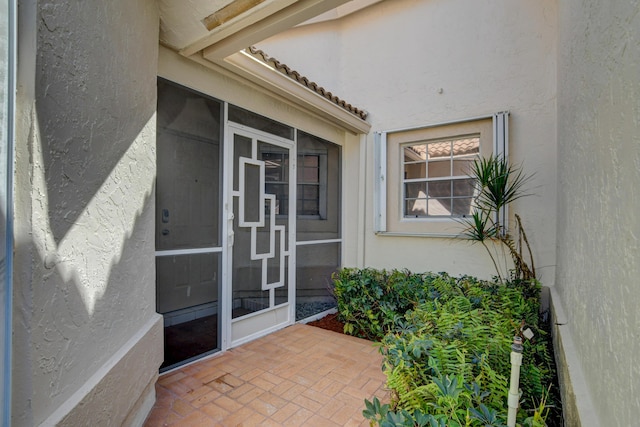 property entrance with stucco siding and a tiled roof