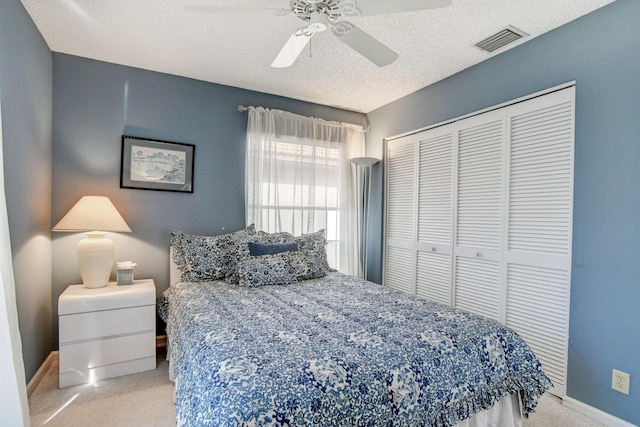 carpeted bedroom featuring visible vents, a textured ceiling, a closet, baseboards, and ceiling fan