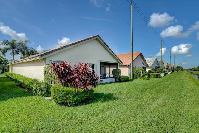 view of property exterior featuring stucco siding, a yard, and a sunroom