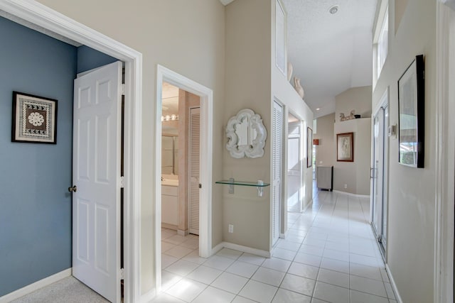 hall featuring light tile patterned floors and baseboards