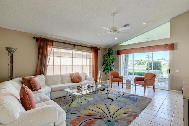 living area featuring visible vents, ceiling fan, vaulted ceiling, light tile patterned floors, and a textured ceiling