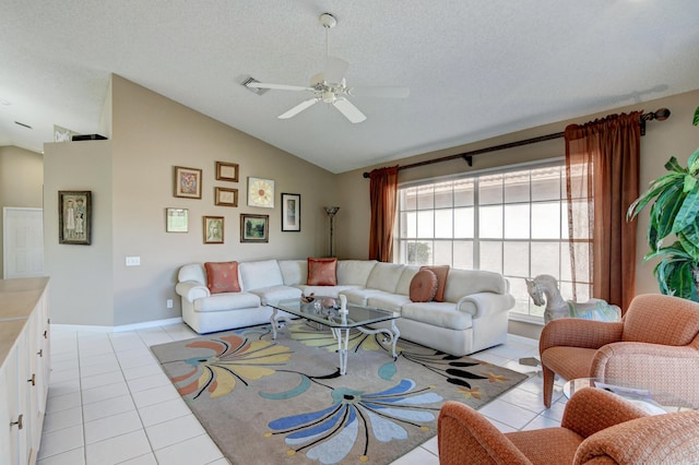 living room featuring ceiling fan, lofted ceiling, light tile patterned floors, and a textured ceiling