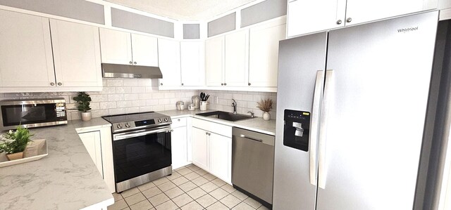 335 S Waverly Pl Unit 7A, Vero Beach, FL 32960 - kitchen with backsplash, under cabinet range hood, appliances with stainless steel finishes, white cabinetry, and a sink