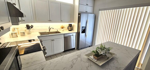 335 S Waverly Pl Unit 7A, Vero Beach, FL 32960 - kitchen with under cabinet range hood, light stone counters, appliances with stainless steel finishes, light tile patterned flooring, and a sink