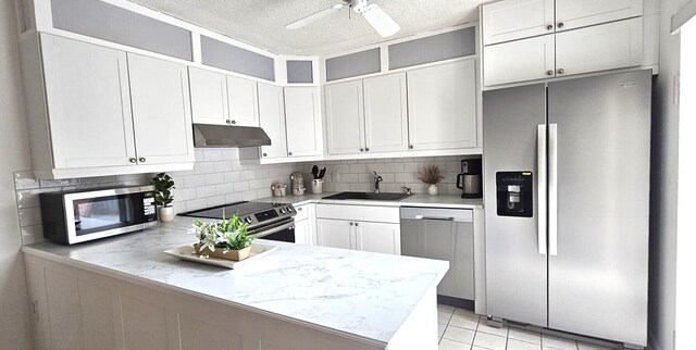 335 S Waverly Pl Unit 7A, Vero Beach, FL 32960 - kitchen featuring under cabinet range hood, a sink, tasteful backsplash, appliances with stainless steel finishes, and a peninsula