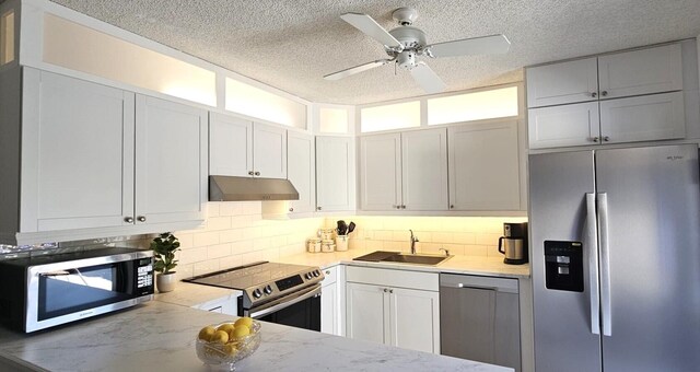 335 S Waverly Pl Unit 7A, Vero Beach, FL 32960 - kitchen featuring light stone counters, a sink, decorative backsplash, stainless steel appliances, and under cabinet range hood
