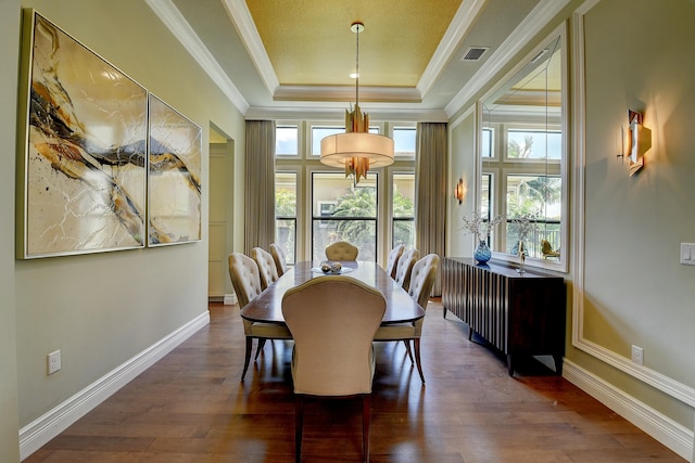 dining area featuring dark wood-style floors, baseboards, visible vents, a tray ceiling, and crown molding