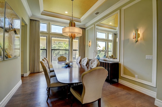 dining area featuring crown molding, hardwood / wood-style flooring, visible vents, and a tray ceiling