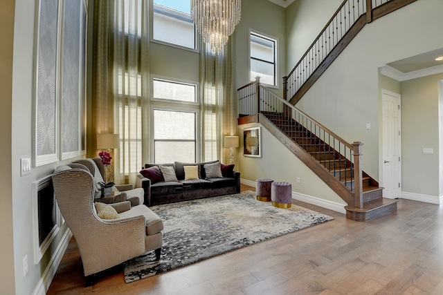 living area with baseboards, stairs, a towering ceiling, and wood finished floors