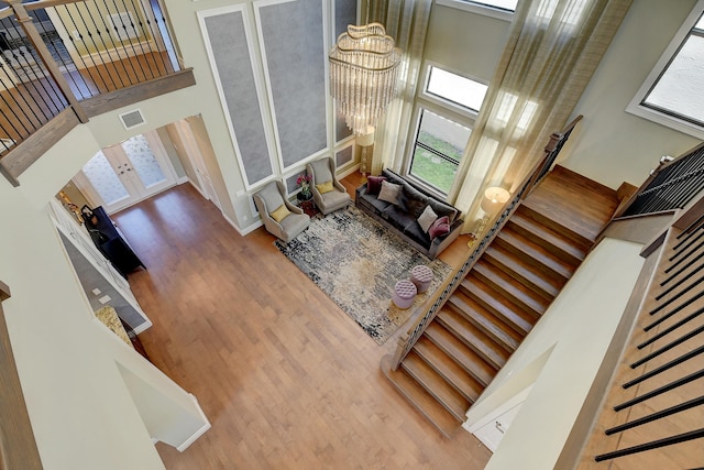 living room with stairs, a notable chandelier, visible vents, and a towering ceiling