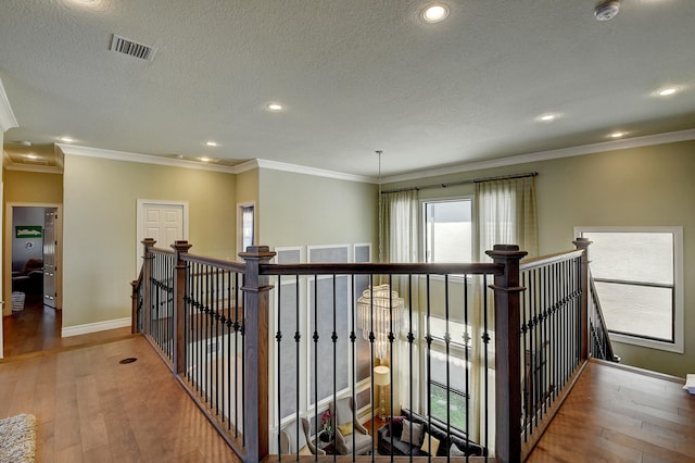 corridor with visible vents, an upstairs landing, and wood finished floors