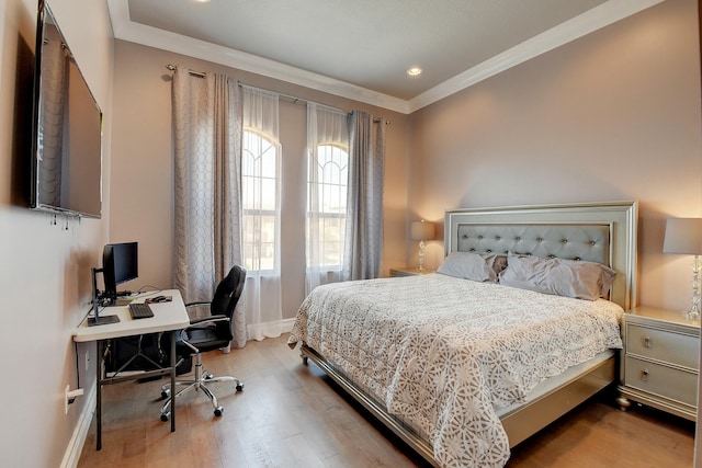 bedroom featuring baseboards, wood finished floors, and crown molding