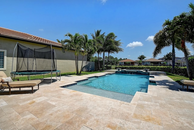 view of swimming pool with a patio, a trampoline, and a pool with connected hot tub