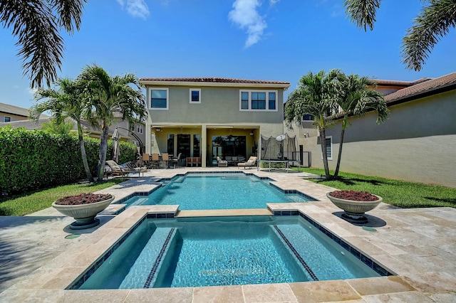 view of pool featuring a patio, a trampoline, a pool with connected hot tub, and fence