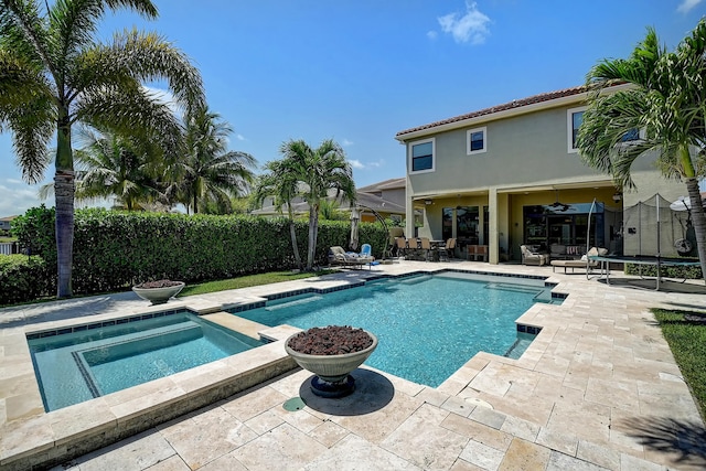 view of swimming pool with a ceiling fan, a patio, a trampoline, a fenced in pool, and an in ground hot tub