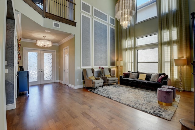 living area with french doors, wood finished floors, a chandelier, and crown molding