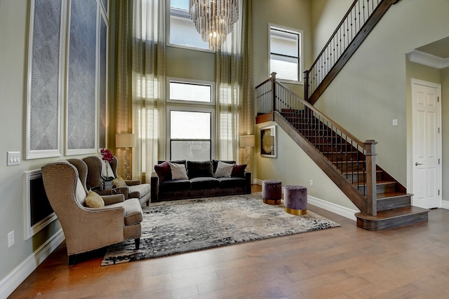 living room with stairway, baseboards, wood finished floors, and a towering ceiling