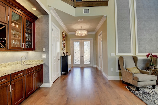 foyer with french doors, light wood-style floors, visible vents, and ornamental molding