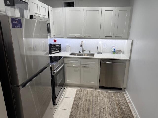 kitchen featuring visible vents, a toaster, appliances with stainless steel finishes, white cabinets, and a sink