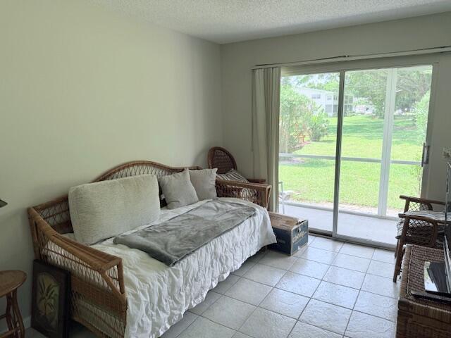 150 Newport J, Deerfield Beach, FL 33442 - bedroom with access to exterior, light tile patterned floors, and a textured ceiling