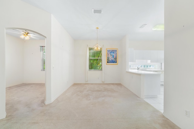 spare room with visible vents, arched walkways, light colored carpet, and a ceiling fan