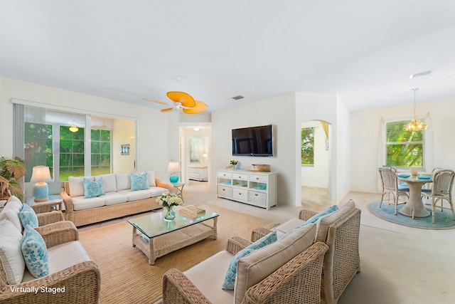 living room featuring ceiling fan with notable chandelier, visible vents, and arched walkways