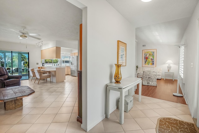 corridor featuring light tile patterned flooring, a textured ceiling, and baseboards