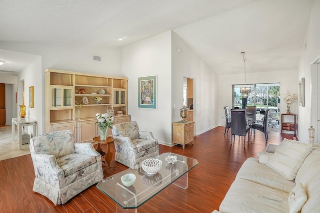 living room featuring high vaulted ceiling, wood finished floors, visible vents, and baseboards