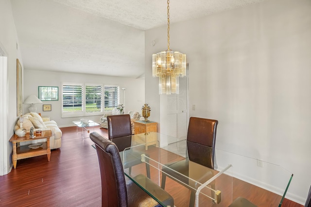 dining space featuring a chandelier, a textured ceiling, baseboards, and wood finished floors