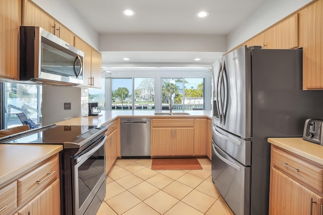 kitchen featuring a sink, light tile patterned flooring, light brown cabinetry, and stainless steel appliances