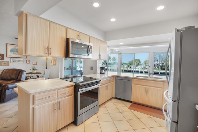 kitchen featuring a sink, stainless steel appliances, a peninsula, and light brown cabinets