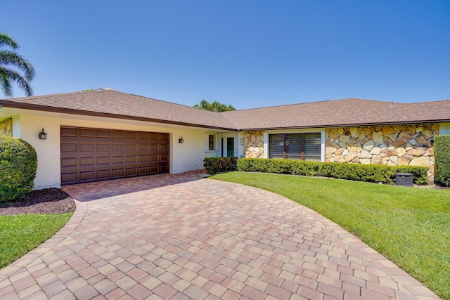 single story home featuring a front yard, stucco siding, decorative driveway, a garage, and stone siding