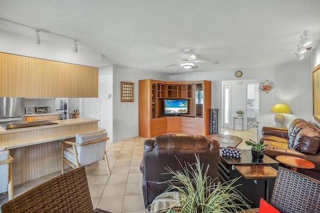 living area with light tile patterned floors, a textured ceiling, ceiling fan, and a toaster