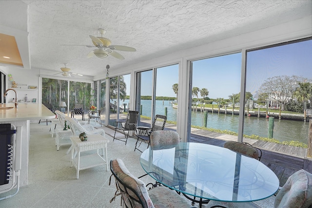 sunroom with a sink, a water view, and ceiling fan