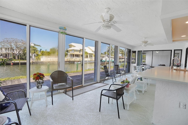 sunroom / solarium with a sink, a water view, and ceiling fan